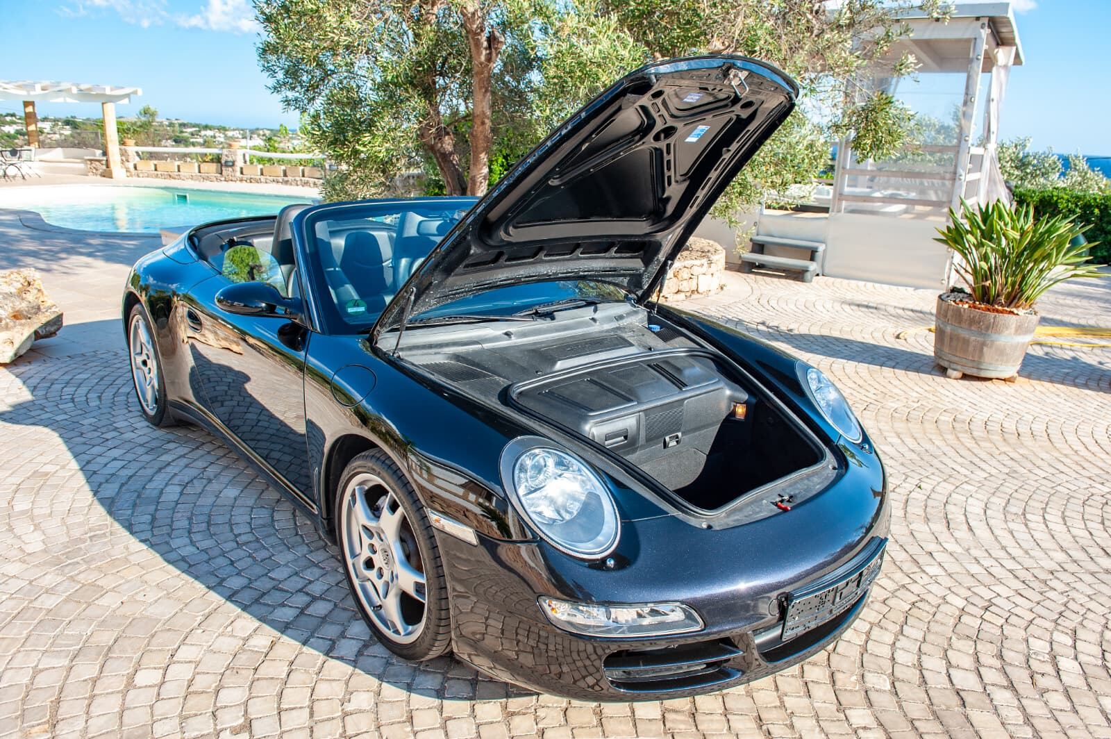 Porsche 911 Carrera 4 Cabriolet con il baule anteriore aperto, davanti alla piscina Porsche 911 Carrera 4 Cabriolet con il baule anteriore aperto, davanti alla piscina