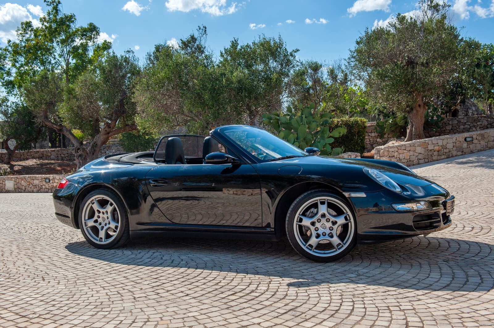 Porsche 911 Carrera 4 Cabriolet, profilo laterale con capote aperta tra gli ulivi Porsche 911 Carrera 4 Cabriolet, profilo laterale con capote aperta tra gli ulivi