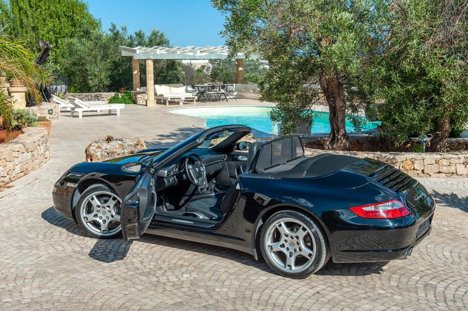 Porsche 911 Carrera 4 Cabriolet, vista 3/4 posteriore a bordo piscina Porsche 911 Carrera 4 Cabriolet, vista 3/4 posteriore a bordo piscina